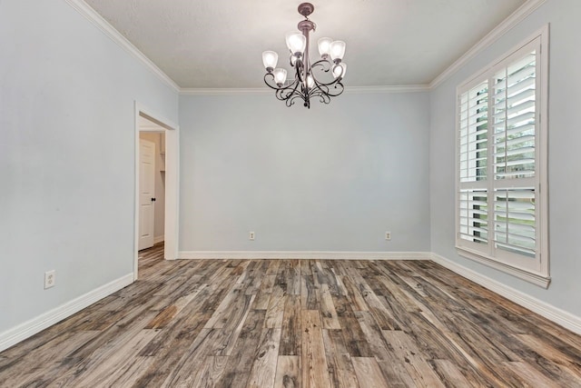 spare room with crown molding, baseboards, a chandelier, and wood finished floors