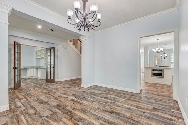 unfurnished dining area with a chandelier, wood finished floors, visible vents, and crown molding