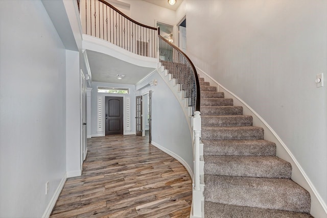 stairs featuring a high ceiling, baseboards, and wood finished floors