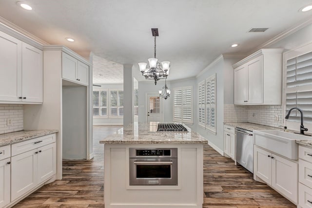 kitchen featuring stainless steel appliances, ornamental molding, visible vents, and a healthy amount of sunlight