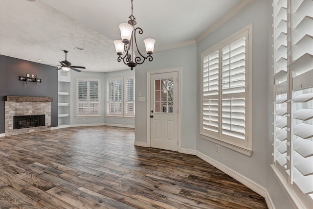 foyer with ceiling fan with notable chandelier, visible vents, baseboards, a brick fireplace, and dark wood-style floors