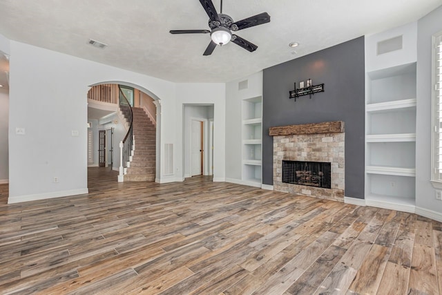 unfurnished living room featuring baseboards, built in shelves, visible vents, and wood finished floors