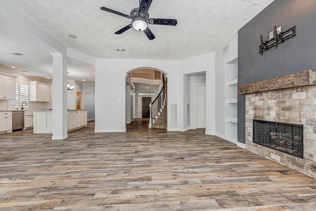 unfurnished living room with light wood-style floors, a fireplace, baseboards, and built in shelves