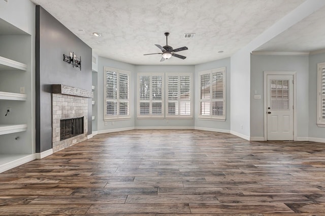 unfurnished living room with built in shelves, dark wood-type flooring, visible vents, baseboards, and a tiled fireplace