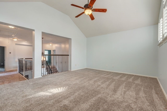 carpeted empty room with a ceiling fan, attic access, high vaulted ceiling, and baseboards