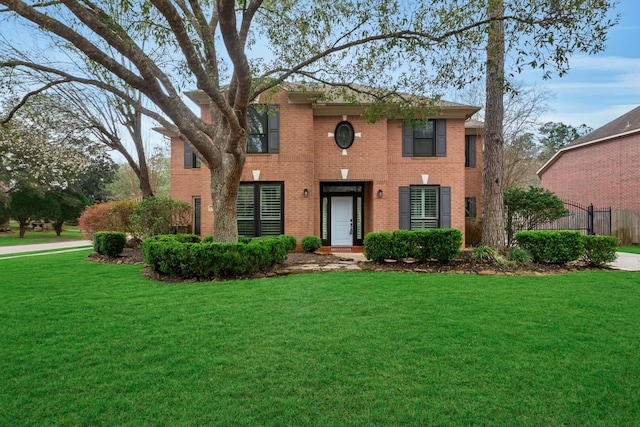 view of front of property featuring a front yard, fence, and brick siding