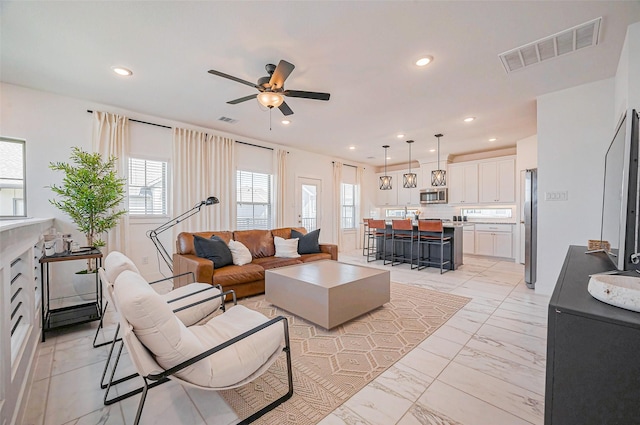 living room with a ceiling fan, recessed lighting, visible vents, and marble finish floor