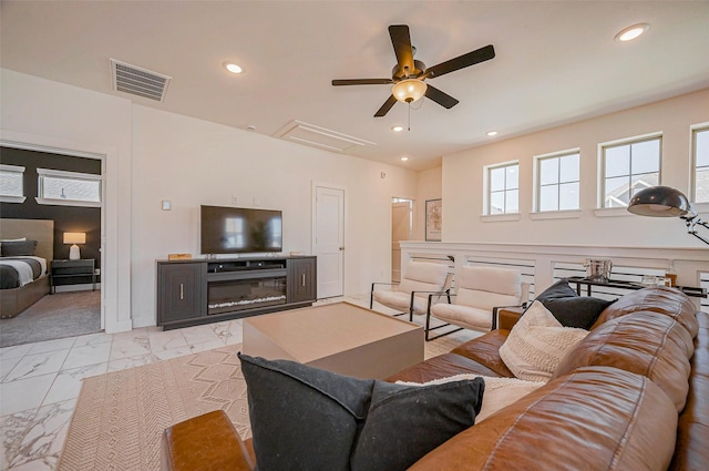 living area featuring visible vents, attic access, recessed lighting, a glass covered fireplace, and marble finish floor