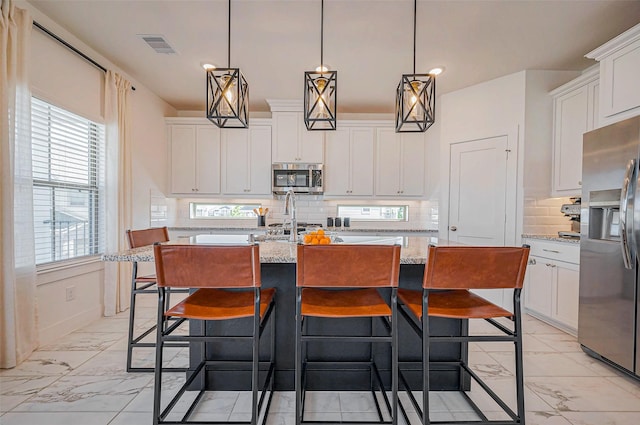 kitchen with marble finish floor, white cabinetry, stainless steel appliances, and an island with sink