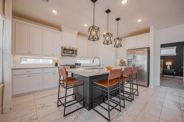 kitchen with marble finish floor, a sink, tasteful backsplash, stainless steel appliances, and white cabinets