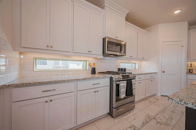 kitchen featuring white cabinetry, backsplash, marble finish floor, and appliances with stainless steel finishes