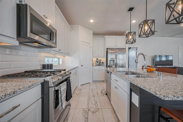 kitchen featuring marble finish floor, a sink, light stone counters, white cabinetry, and stainless steel appliances