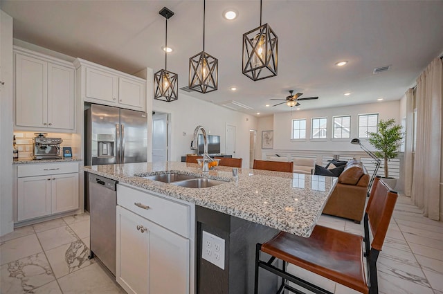 kitchen featuring open floor plan, recessed lighting, marble finish floor, stainless steel appliances, and a sink