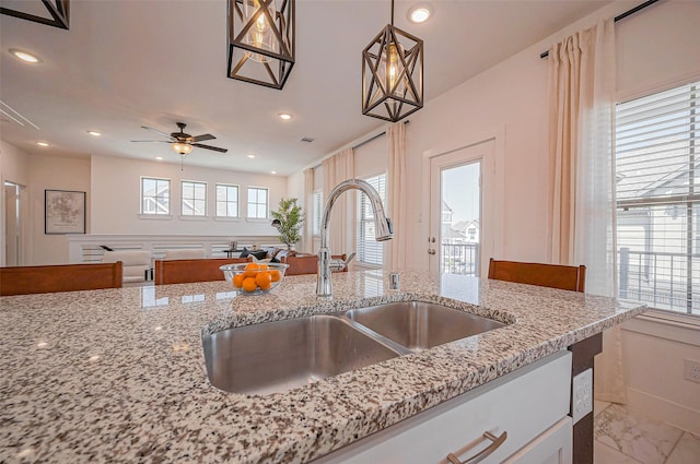 kitchen with light stone counters, recessed lighting, marble finish floor, and a sink