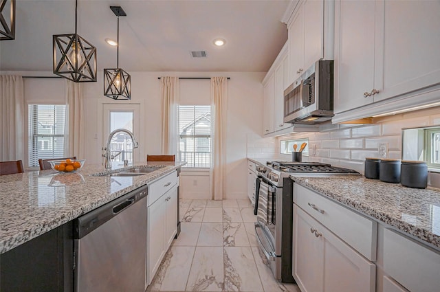 kitchen featuring backsplash, appliances with stainless steel finishes, white cabinets, marble finish floor, and a sink