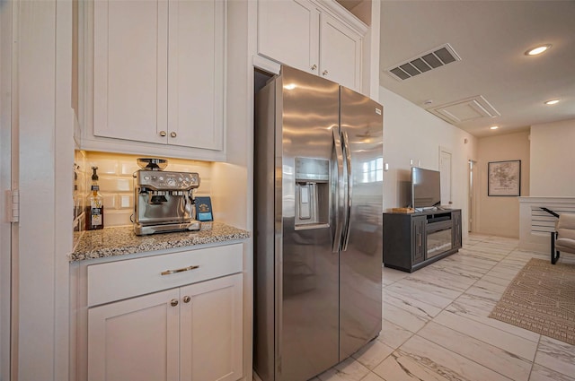 kitchen featuring light stone counters, visible vents, stainless steel refrigerator with ice dispenser, white cabinetry, and marble finish floor