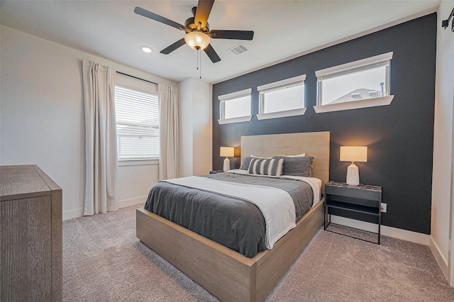 carpeted bedroom with visible vents, baseboards, and a ceiling fan