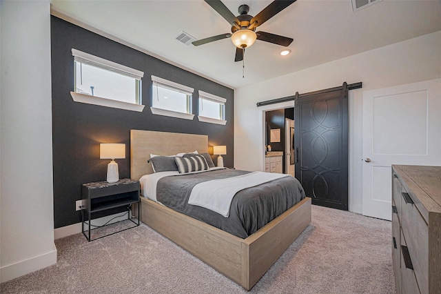 bedroom with light carpet, ensuite bathroom, a barn door, baseboards, and ceiling fan