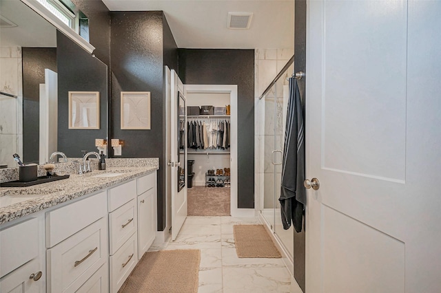 full bathroom featuring visible vents, double vanity, a sink, a shower stall, and marble finish floor