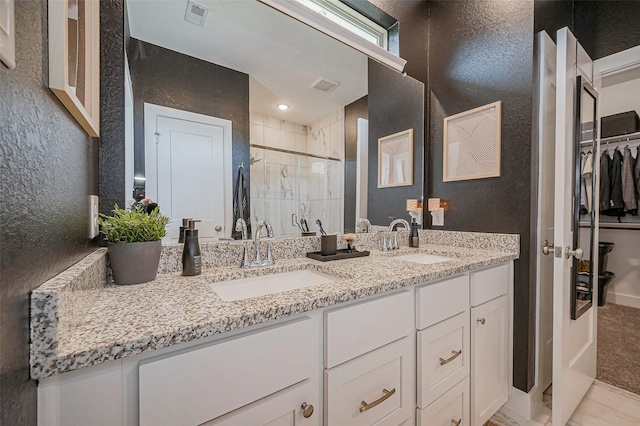 bathroom with a sink, visible vents, a stall shower, and a textured wall