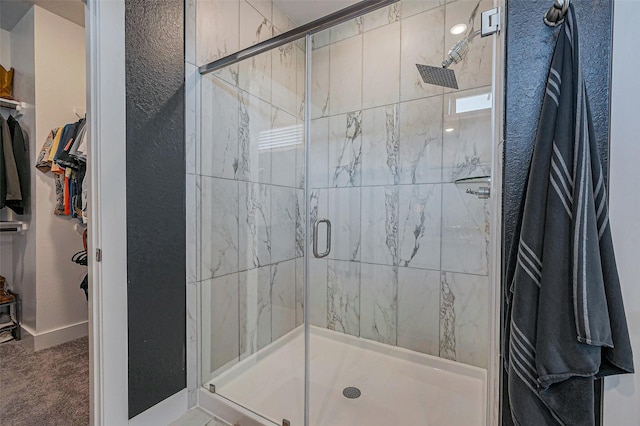 bathroom featuring a spacious closet and a shower stall