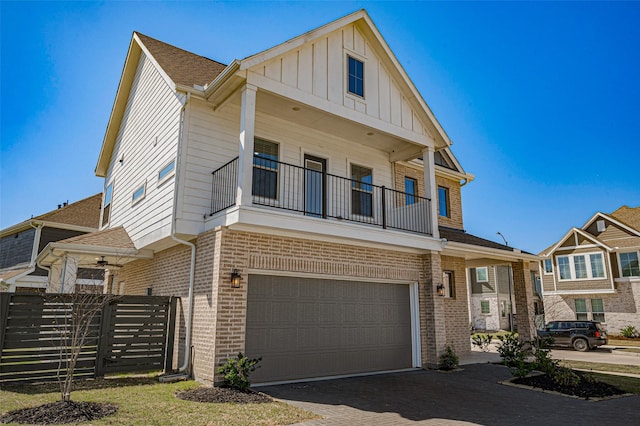 view of property with brick siding, board and batten siding, fence, a balcony, and driveway