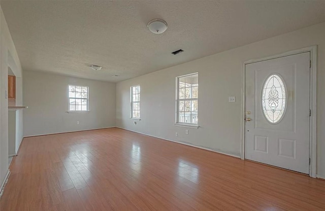 foyer entrance featuring light wood-type flooring, visible vents, and a textured ceiling