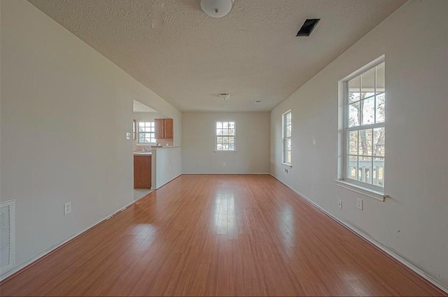 unfurnished room with a textured ceiling and light wood-type flooring