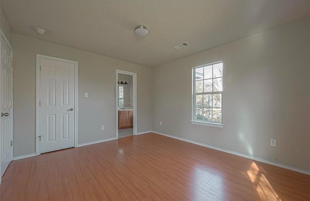 unfurnished room featuring baseboards, visible vents, and wood finished floors
