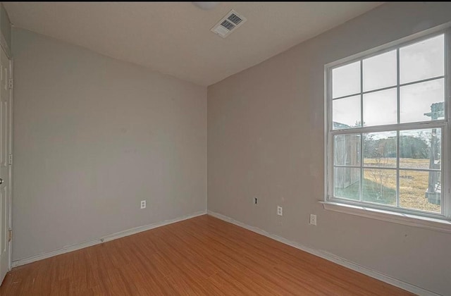 empty room featuring baseboards, visible vents, and light wood finished floors