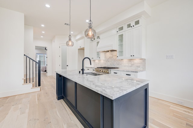 kitchen with white cabinetry, light wood-type flooring, decorative backsplash, light stone countertops, and custom range hood