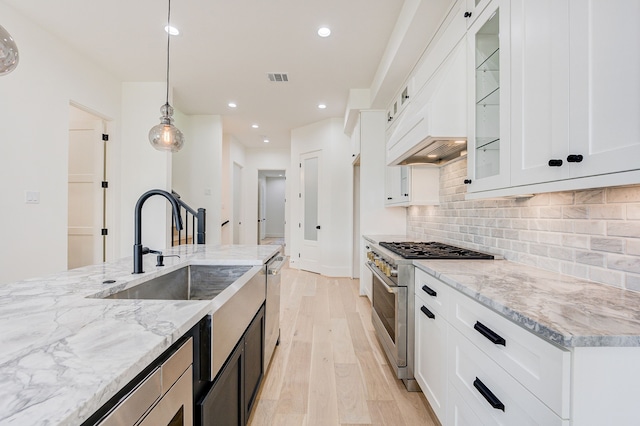 kitchen with visible vents, backsplash, appliances with stainless steel finishes, light stone countertops, and light wood-type flooring