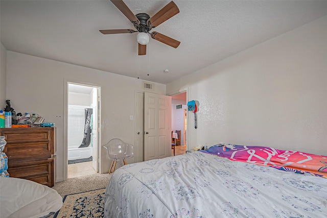 bedroom featuring light colored carpet, visible vents, ceiling fan, a textured ceiling, and ensuite bath