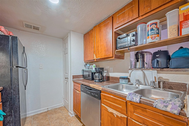 kitchen with visible vents, freestanding refrigerator, a sink, a textured ceiling, and dishwasher