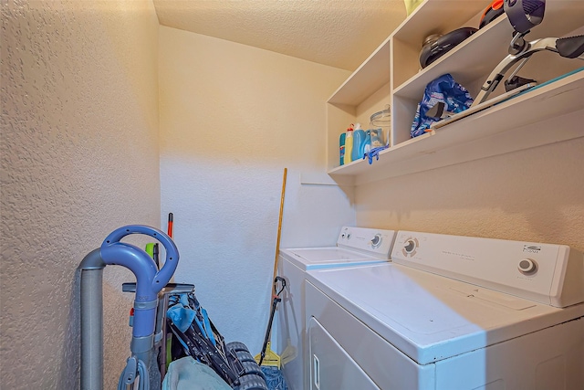 clothes washing area with laundry area, separate washer and dryer, a textured ceiling, and a textured wall