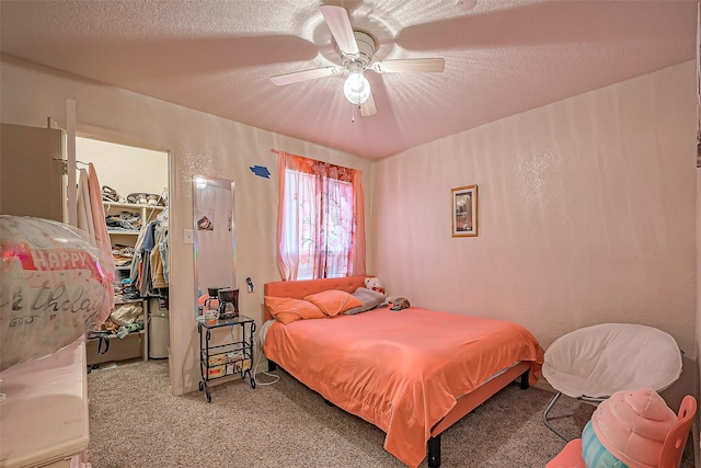 bedroom with a textured ceiling, a spacious closet, a closet, and carpet flooring