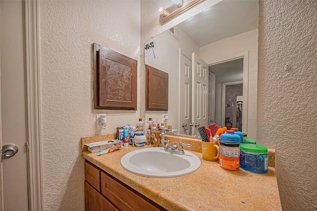 bathroom featuring a textured wall and vanity