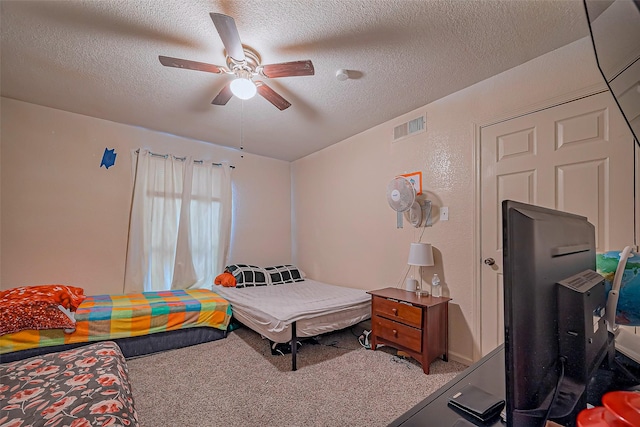 bedroom with a ceiling fan, visible vents, carpet floors, and a textured ceiling