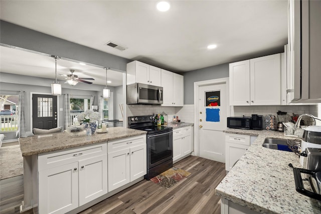 kitchen with dark wood-style flooring, visible vents, decorative backsplash, white cabinetry, and black appliances