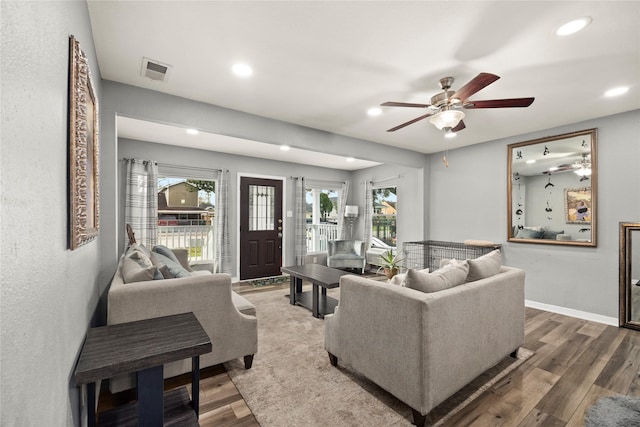 living room with baseboards, visible vents, wood finished floors, and recessed lighting