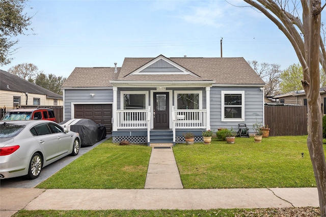 view of front facade with an attached garage, covered porch, fence, roof with shingles, and a front yard