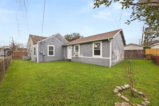 rear view of house with a fenced backyard, a lawn, and roof with shingles