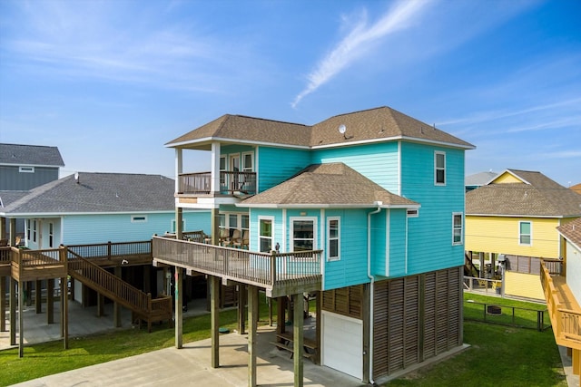 rear view of house with a balcony, fence, a yard, roof with shingles, and a carport