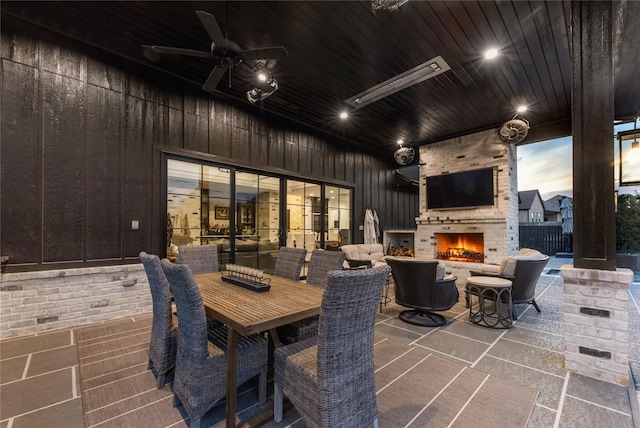 view of patio / terrace with an outdoor brick fireplace, outdoor dining area, and ceiling fan