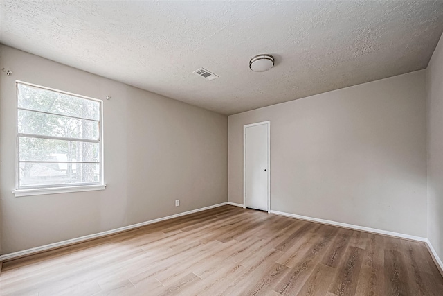 unfurnished room with baseboards, visible vents, a textured ceiling, and light wood finished floors