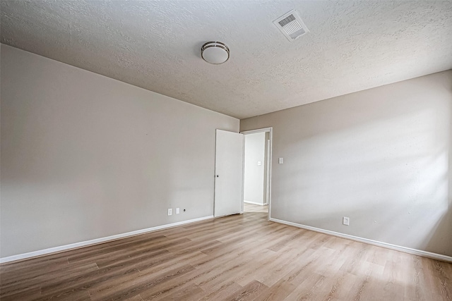 unfurnished room with visible vents, a textured ceiling, baseboards, and wood finished floors