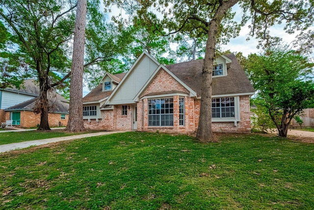 view of front of property with a front lawn, roof with shingles, and brick siding