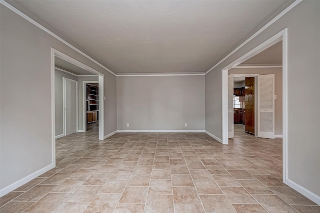 spare room featuring light tile patterned floors, baseboards, and crown molding