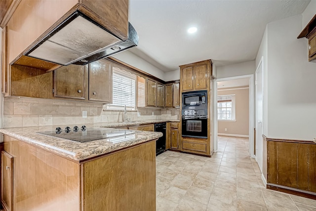 kitchen featuring island range hood, a sink, backsplash, black appliances, and plenty of natural light