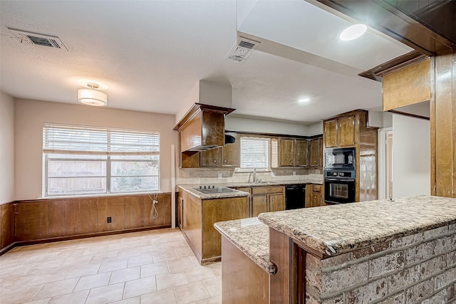 kitchen with black appliances, wainscoting, a peninsula, and visible vents